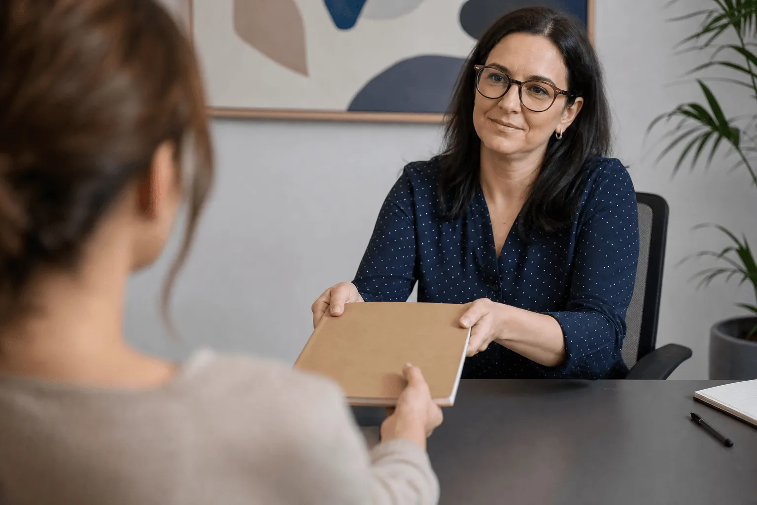 A clinician handing a printed clinical pathway document to a client across a desk.